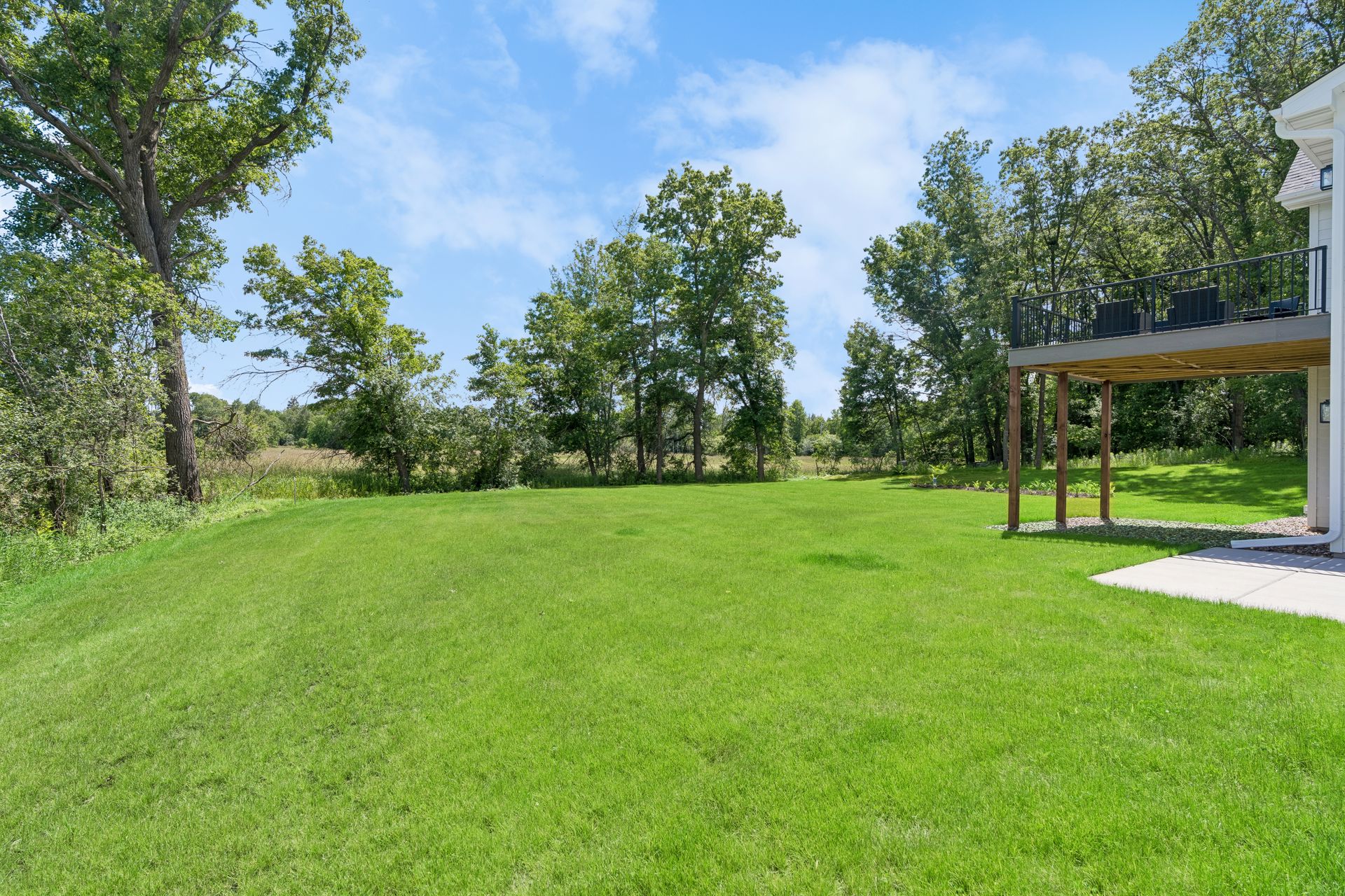 Backyard with mature trees, green lawn and elevated deck